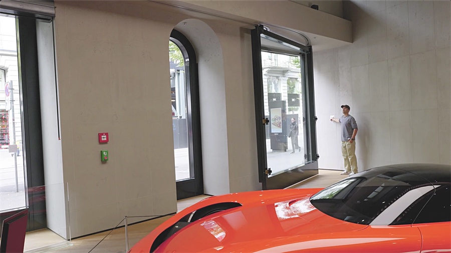 Im Studio: das Schleusentor schwenkt auf, eine Person am Schalter, davor ein oranges Showcar