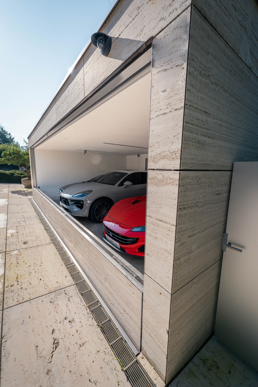 Offene Garage von der Seite, Sportwagen hinter der versenkten Front