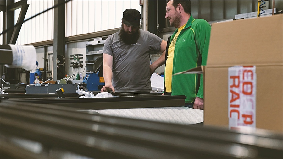 Zwei Metallbauer von HIRT kinetics besprechen ein Bauteil in der Werkstatt in Mollis