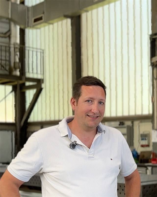 Metallbaukonstrukteur von HIRT kinetics in der Werkstatt, hinter ihm ein Plan