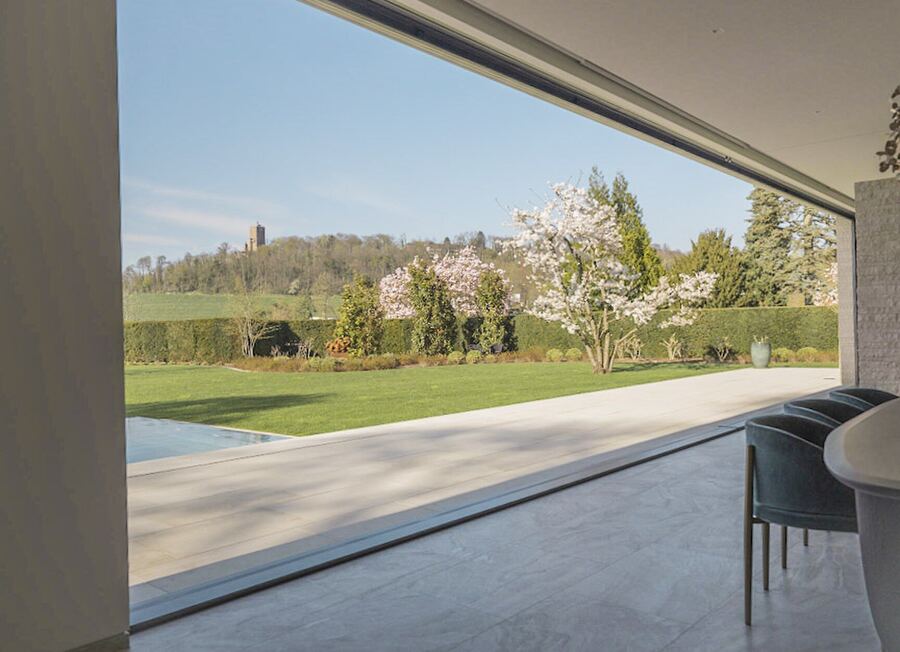 Blick durch eine rahmenlose Glasfront in den Garten